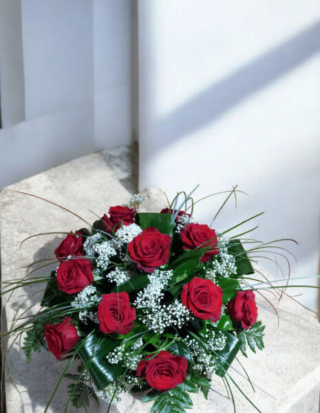 Centrotavola con rose rosse, gypsophila e verdi decorativi.